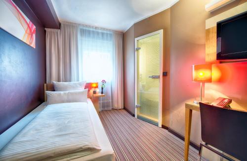 Habitación de hotel con cama y TV en Leonardo Boutique Hotel Munich en Múnich
