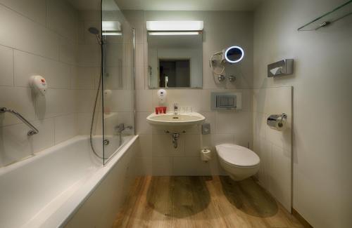 a bathroom with a sink and a toilet and a shower at Leonardo Hotel Köln in Cologne