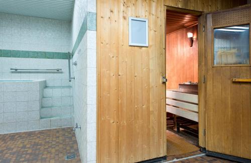 a bathroom with a shower and a wooden door at Leonardo Hotel Köln in Cologne