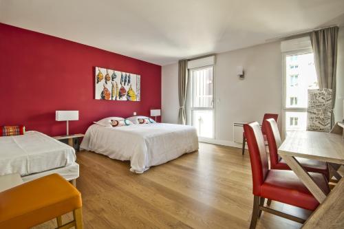 a bedroom with two beds and a red wall at Résidence Quai Sud-Le Cartier in Saint Malo