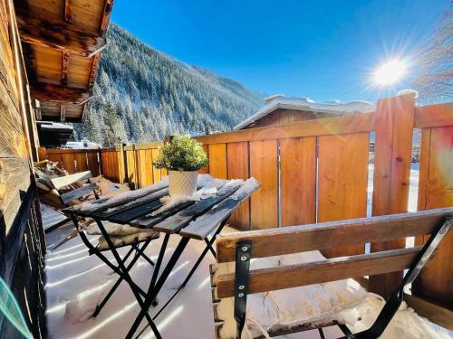 a patio with a table and a bench in the snow at Chalet le petit Nicolas, jacuzzi, vue Mont Blanc in Chamonix-Mont-Blanc