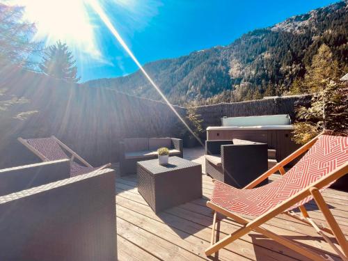 a deck with chairs and a table and the sun at Chalet le petit Nicolas, jacuzzi, vue Mont Blanc in Chamonix-Mont-Blanc