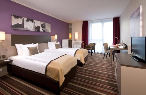 um quarto de hotel com duas camas e uma televisão de ecrã plano em Leonardo Hotel Hannover Airport em Hanôver
