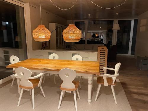 a dining room table with white chairs and two lights at Ferien- und Seminarhaus Seeger in Haunsheim