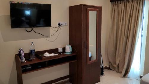 Zimmer mit einem TV an der Wand neben einer Tür in der Unterkunft MercuryFM 101 Yarl Mercury Inn - Jaffna in Jaffna