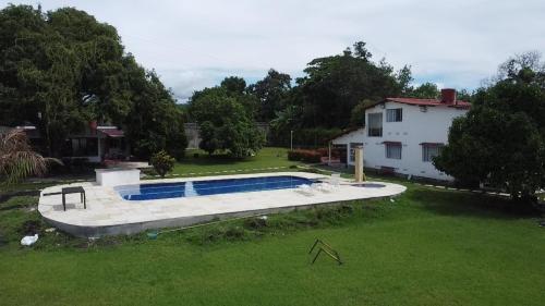 a swimming pool in a yard next to a house at VILLA ALEJANDRIA - CABAÑA LAMARIQUITA-CABAÑA ORQUIDEA-CABAÑA CARAMBOLa in Mariquita
