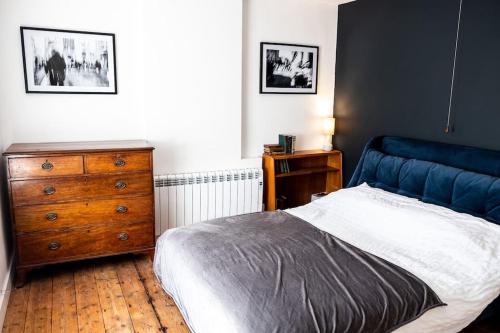 a bedroom with a blue bed and a wooden dresser at Charming Victorian Townhouse Near Oxford in Witney