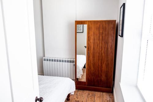 a bedroom with a wooden door and a mirror at Charming Victorian Townhouse Near Oxford in Witney