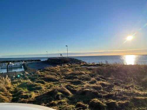 a beach with the sun setting over the water at Pia’s Country House in Båstad