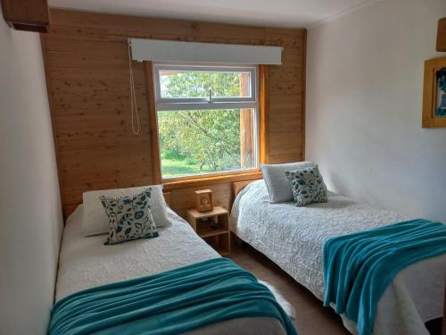 um quarto com 2 camas e uma janela em Cabañas Chaya Mapu em Puerto Aisén