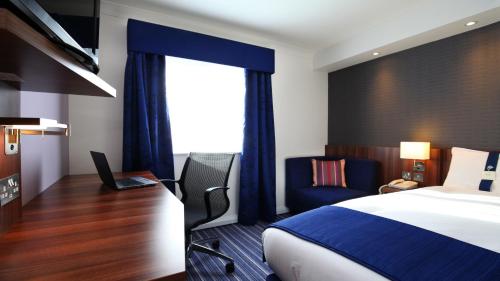 a hotel room with a bed and a desk with a laptop at Holiday Inn Express York by IHG in York