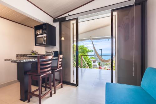 a kitchen and living room with a bar and a balcony at Hotel Villas de la Selva in Manuel Antonio