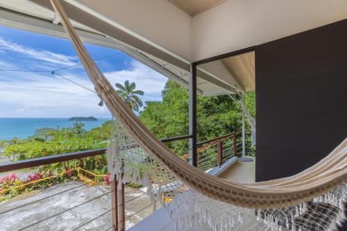 a hammock in a room with a view of the ocean at Hotel Villas de la Selva in Manuel Antonio
