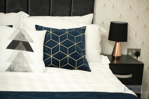 Una cama con almohadas azules y blancas y una lámpara. en Modern City centre apartment WIFI Netflix en Nottingham