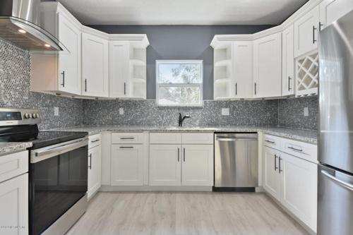 una cocina con armarios blancos y electrodomésticos de acero inoxidable en The Jewel of Jacksonville en Jacksonville