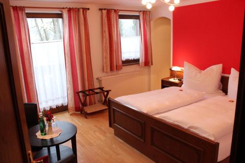 a bedroom with a red wall with a bed and two windows at Pension Wolfgangsee in St. Wolfgang