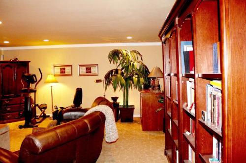 ein Wohnzimmer mit einem Ledersofa und einer Pflanze in der Unterkunft Shared Home in Inglewood