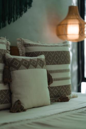 a pile of pillows on a bed with a lamp at San Trópico Boutique Hotel & Peaceful Escape in Puerto Vallarta
