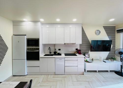 una cocina blanca con armarios y electrodomésticos blancos en Atlantic Coast Apartment - Playa Del Inglés, en Playa del Inglés