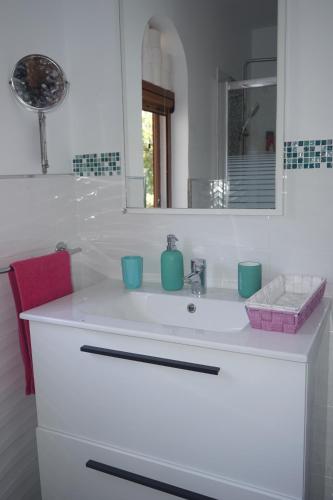 Baño blanco con lavabo y espejo en Bungalow Luisy, en Maspalomas