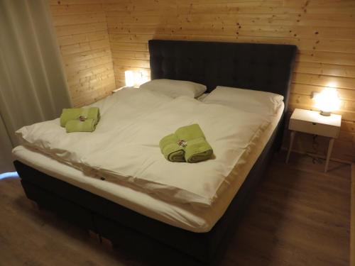 ein großes Bett mit zwei grünen Kissen darauf in der Unterkunft EifelGlückVII in Rieden
