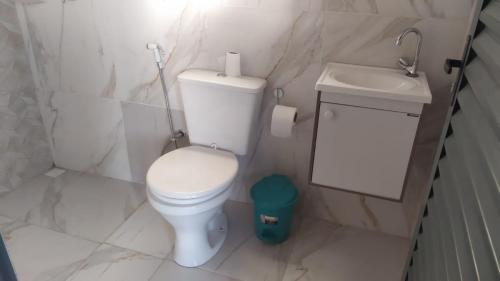a white bathroom with a toilet and a sink at Casa Pirineus in Pirenópolis