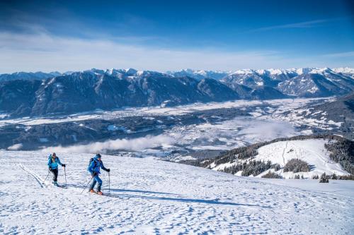 two people skiing down a snow covered mountain at Pension Linder in Seeboden
