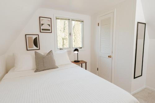 a white bedroom with a white bed and a window at Modern A-Frame with Hot Tub in Essexville