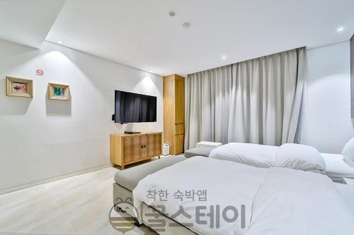 a bedroom with two beds and a flat screen tv at Golden Hotel Incheon in Incheon