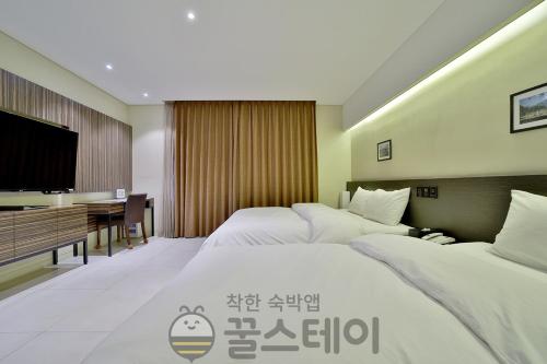 a hotel room with two beds and a flat screen tv at Golden Hotel Incheon in Incheon