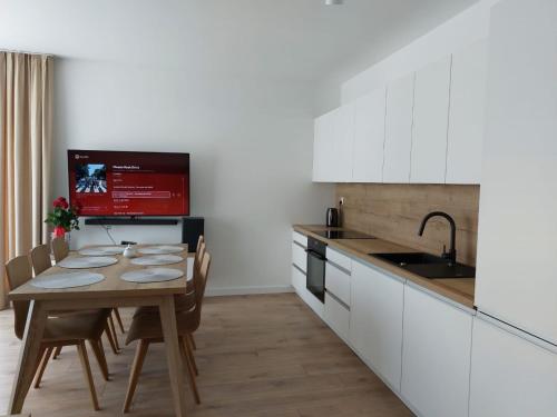 a kitchen with white cabinets and a table with chairs at Apartament Zamkowa Park Węgorzewo in Węgorzewo