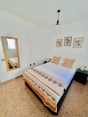 a white bedroom with a bed and a mirror at Encantadora Habitación Privada cerca del mar in Málaga