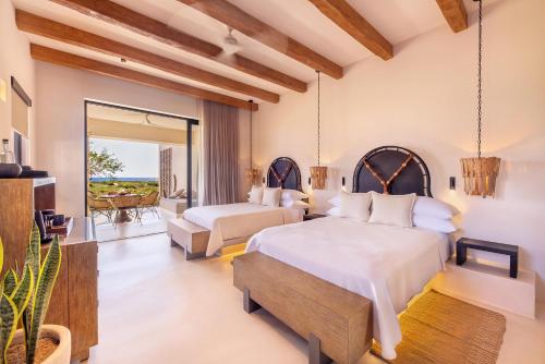 a bedroom with two beds and a balcony at Kimpton Mas Olas Resort and Spa, an IHG Hotel in El Pescadero