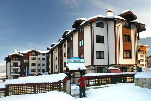 a person standing in the snow in front of a hotel at Winslow Highland Bansko - Apartment Giovanni, ул Валевица 7 кв Грамадето in Bansko