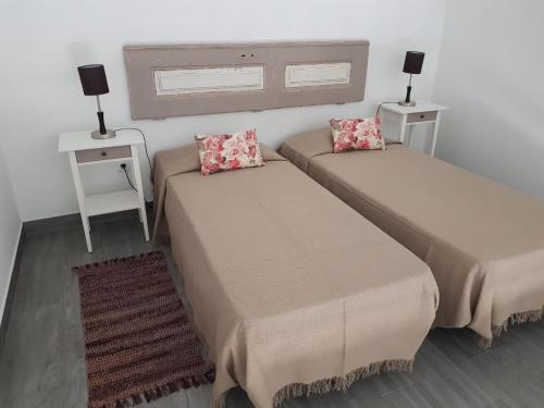 2 camas en una habitación con 2 mesas y 2 lámparas en Casa da Praça en Ponte de Sor