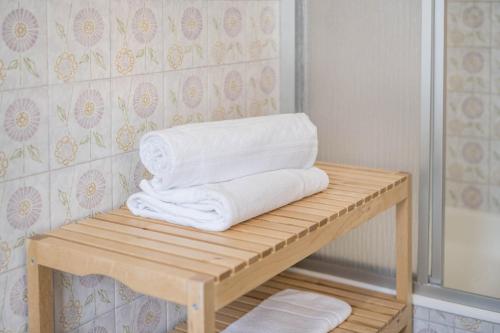 a stack of towels on a wooden shelf in a bathroom at App Garden Lanzmaria in Sorafurcia