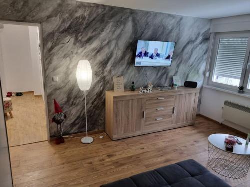 a living room with a tv on a marble wall at Studio Apartman Bojana 34m2,free wifi,parking in Sisak