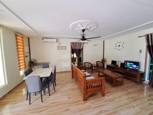 Rayyan Ashraf homestay في كوتا بْهارو: غرفة معيشة مع طاولة وغرفة طعام