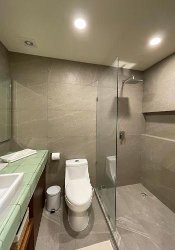 a bathroom with a toilet and a glass shower at Beautiful Loft Steps From The Beach in Punta Cocos - D101 in Holbox Island