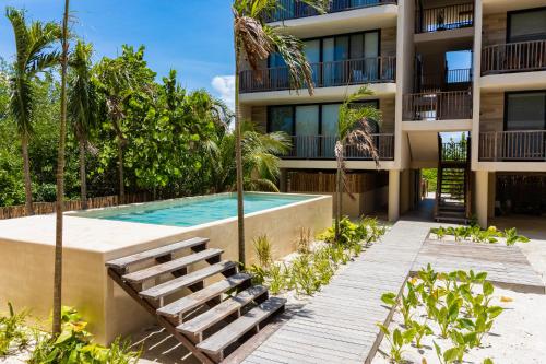 an apartment building with a swimming pool and a resort at D101 Beautiful Loft Steps From The Beach - Punta Cocos in Holbox Island
