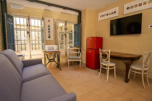 a living room with a couch and a table and a refrigerator at Apartamentos Sharis in Jerez de la Frontera
