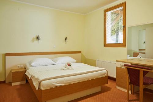 1 dormitorio con cama, mesa y espejo en Thermal Apartments Lendava, en Lendava