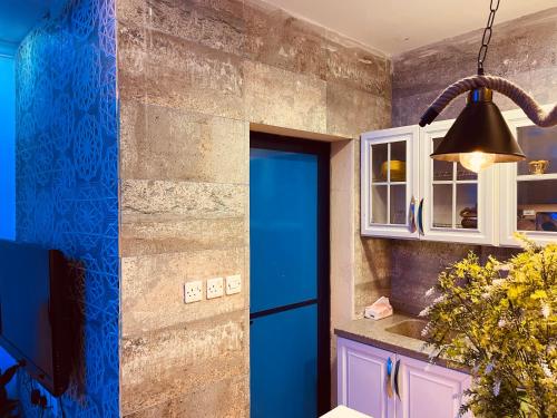 a kitchen with a blue door and aendant light at بيتي بلس للغرف الفندقية- مدخل مستقل in Riyadh Al Khabra