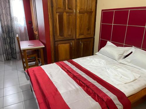 a bedroom with a red and white bed and a table at Complexe Meublé PEPON in Douala
