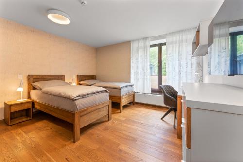 1 dormitorio con 2 camas, escritorio y ventana en Apartment Adélka 203 - Residence Koubek en Špindlerův Mlýn