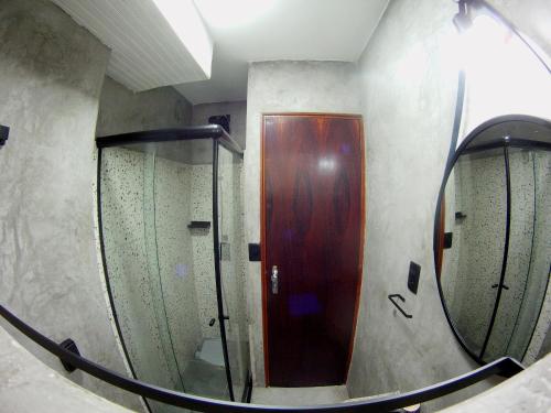 a bathroom with a wooden door and a mirror at Apartamento Dona Frida Prainha com WiFi pé na areia in Caraguatatuba