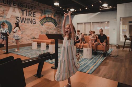 a little girl standing on a stage with her arms in the air at The Lodge at Camp Margaritaville in Pigeon Forge