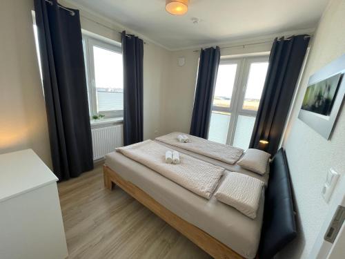 a bedroom with a bed with two towels and two windows at Zuhause Woanders - Bleicherstraße in Wildeshausen