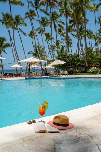 a hat and a book next to a swimming pool at Hotel Casa Hemingway in Juan Dolio