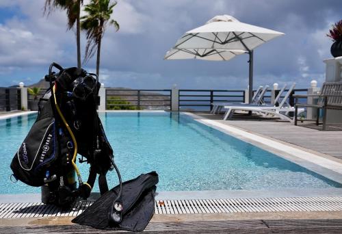 a person is standing next to a swimming pool at Quill Gardens Boutique Hotel in Oranjestad
